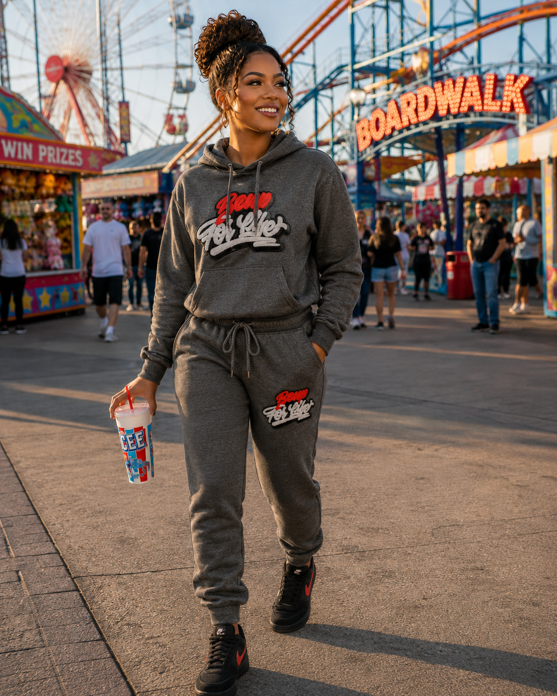 Woman wearing a gray BE UP FOR LIFE chenille patch jogger set walking through an amusement park.