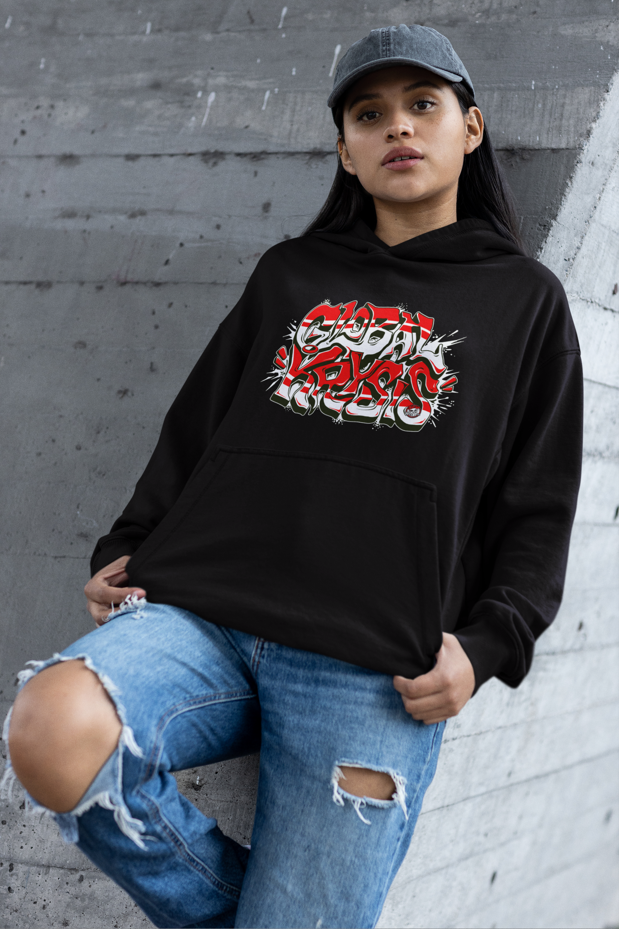 Woman wearing a black Be Up For Life Global Krysis hoodie with a red, white and black graffiti-style logo.
