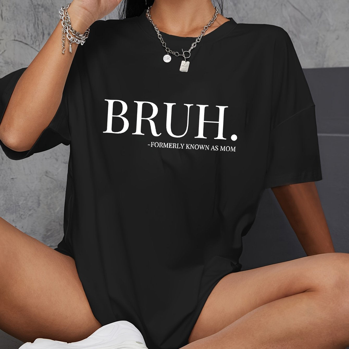 A person wearing a black crewneck T-shirt with the word 'BRUH.' printed on the front.