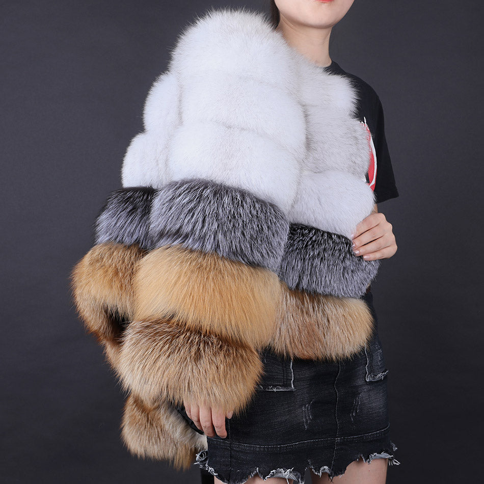 Fur shawl with white, gray, and brown sections held by a person against a dark background