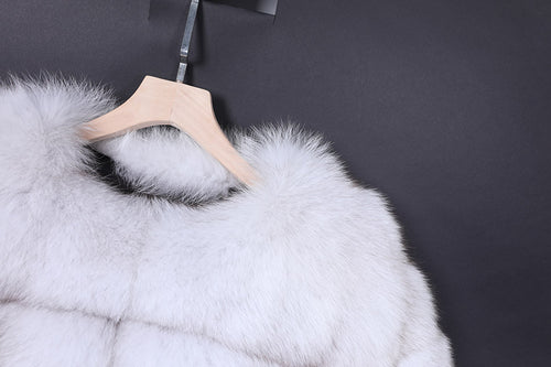 White fur coat on a wooden hanger against a dark background